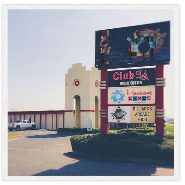 Photo shows the outside of the Hurricane Lanes facility in Destin, FL, and its sign reading Hurricane Lanes, Rupert's Sports Bar, and Club LA